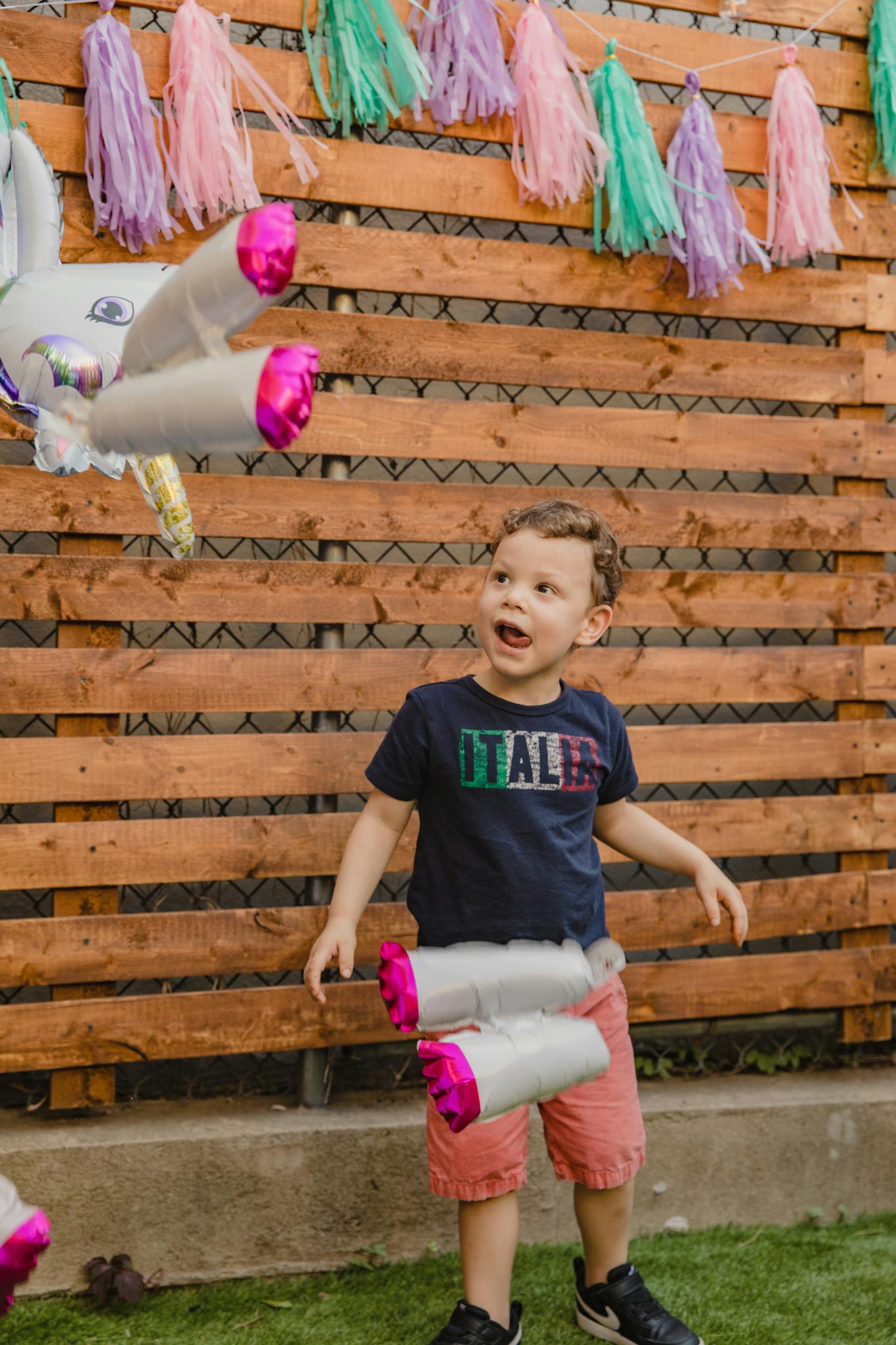 A joyful child plays with balloons during an outdoor birthday celebration.