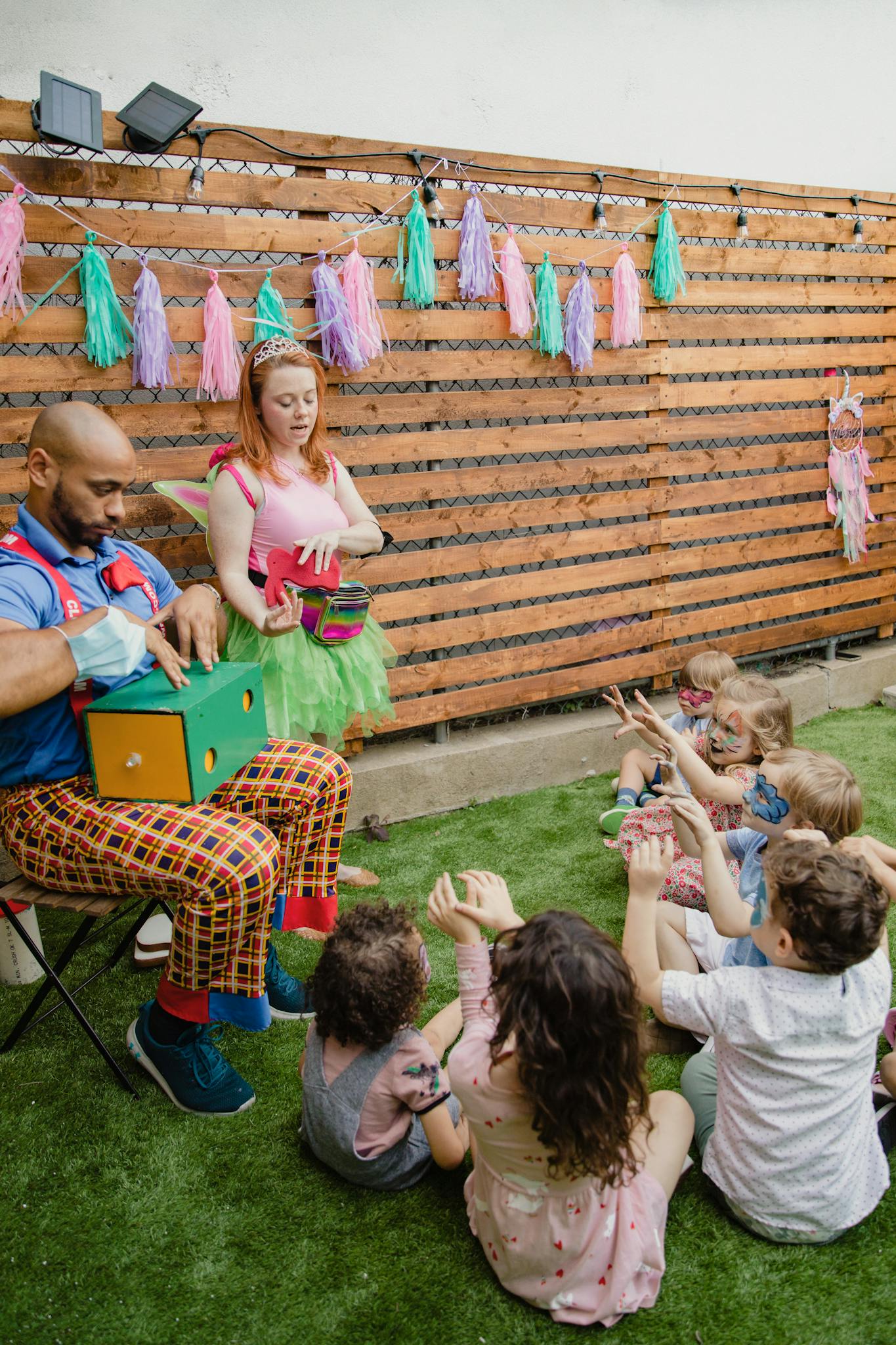 Children enjoying a lively outdoor party with clowns and colorful decorations.